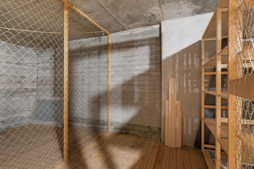An empty basement with concrete foundation walls and empty wooden storage shelves.
